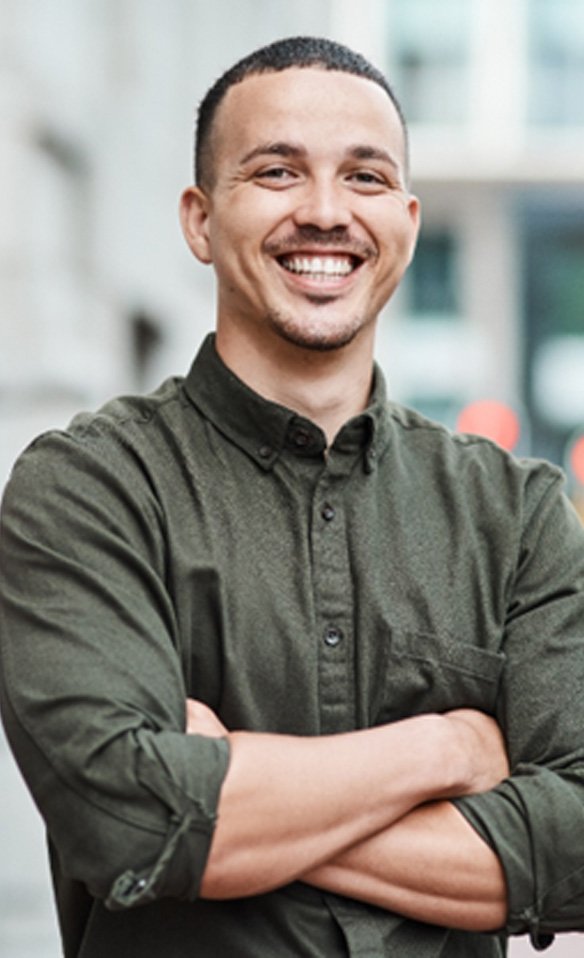 Man in green shirt smiling with arms folded