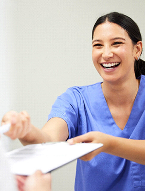 Dental assistant smiling while handing patient form