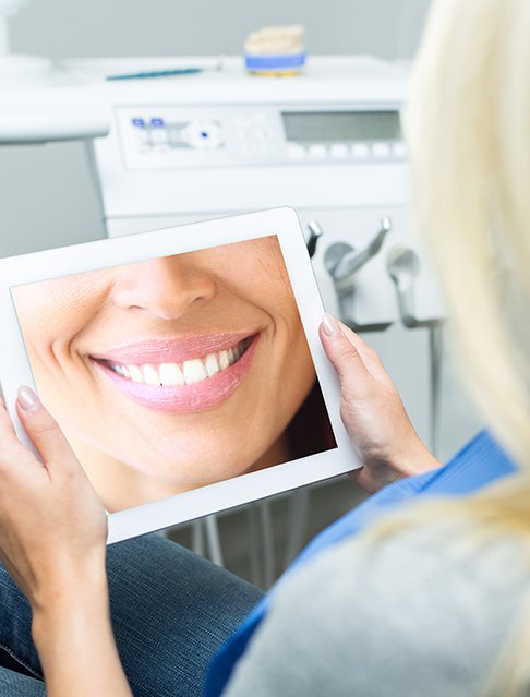 Woman looking at virtual smile design on tablet computer