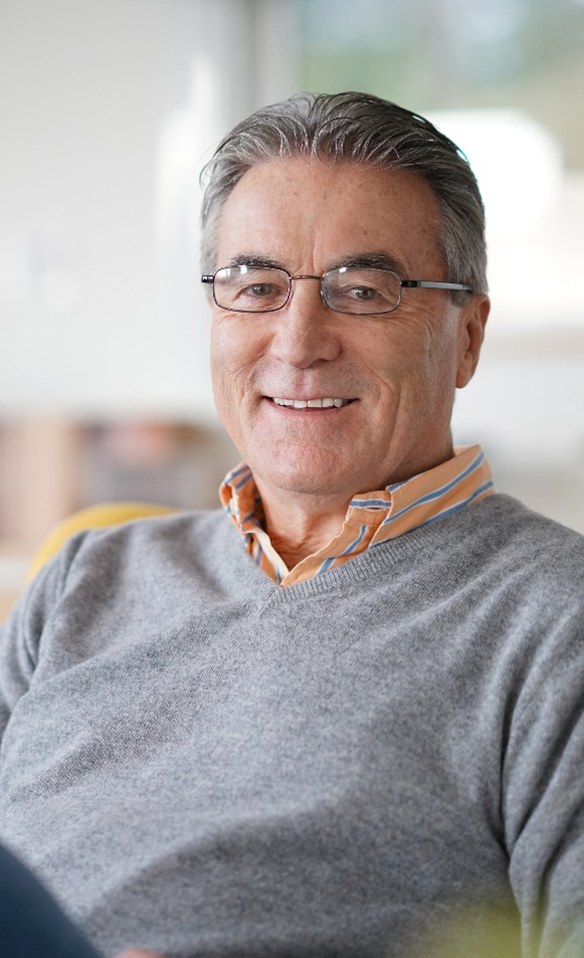 Senior man in grey shirt sitting and smiling