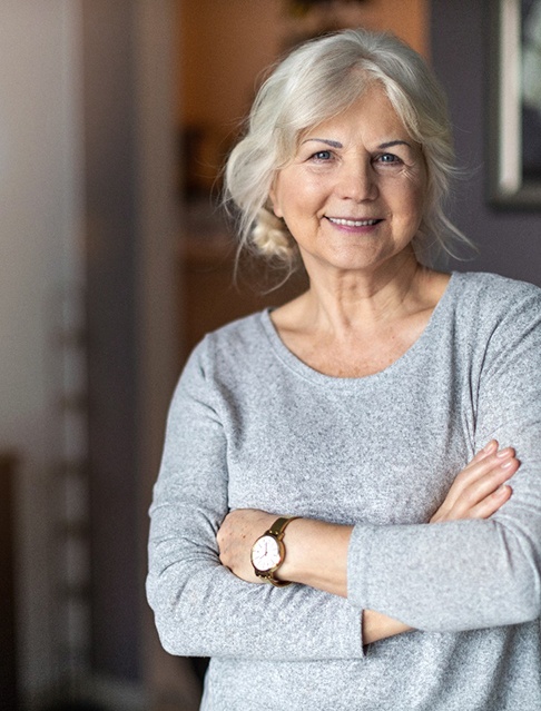 Senior woman in house with her arms folded 