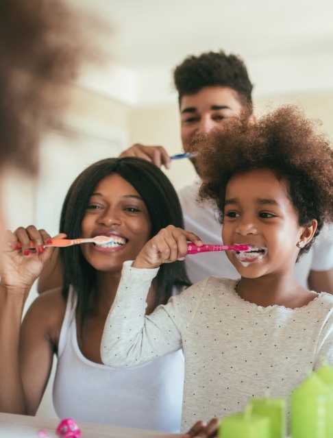 Family brushing teeth together to prevent dental emergencies