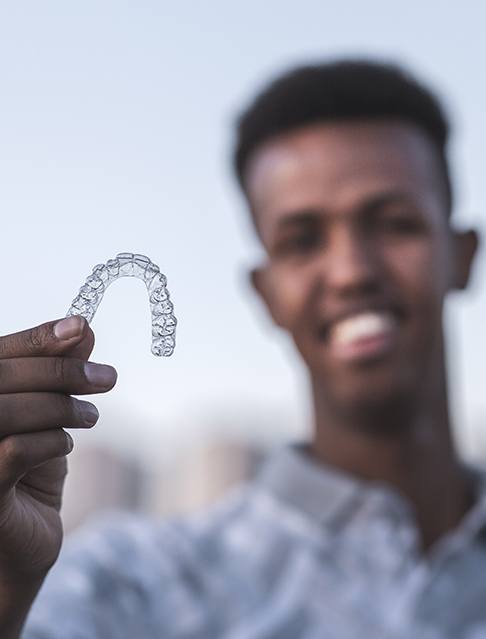 Man holding an Invisalign clear braces tray