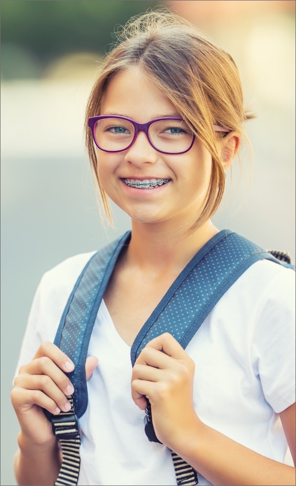 Young girl with traditional orthodontics smiling