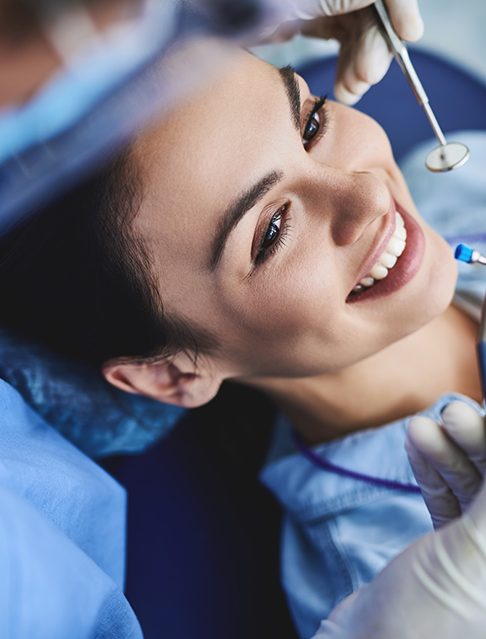 Smiling patient receiving dental checkup and teeth cleaning