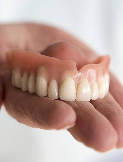 Hand holding a full denture