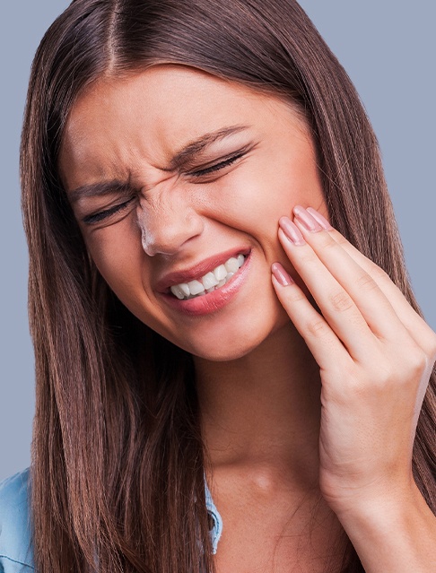 Woman with dental health concern holding cheek in pain