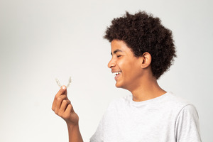 Teenage boy looking at his Invisalign aligners