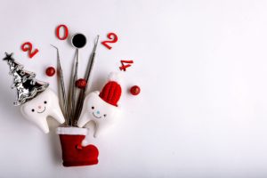 Toy teeth decorated for the holidays next to dental instruments for 2024