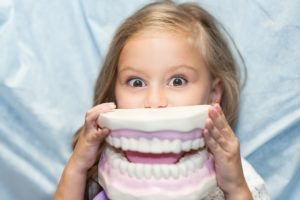 Young girl playing with large dental mold
