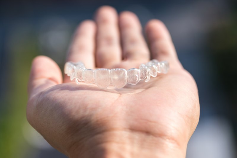 person holding a clear aligner in their hand